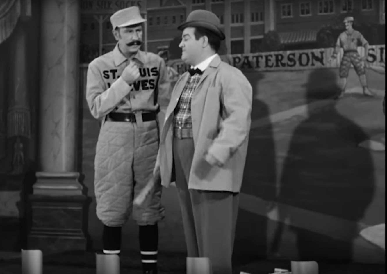 Image of Abbott and Costello performing their famous routine, "Who's on First?" Costello, a native of Paterson, liked to pay homage to his hometown, as seen on an outfield fence sign.  Image: Cropped screen capture from  The Naughty Nineties, ©1945, Universal Pictures. Consistent with Fair Use Doctrine.