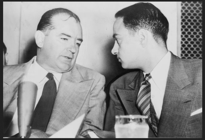 Sen. Joseph McCarthy (left) chats with his attorney Roy Cohn during Senate subcommittee hearings on the McCarthy-Army dispute. United Press International telephoto. United States Library of Congress digital ID cph.3c14995, Public Domain.